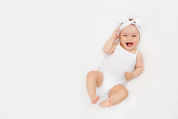 Smiling Newborn Baby On A White Bed At Home The Concept Of A Happy Healthy Baby A Place For Text